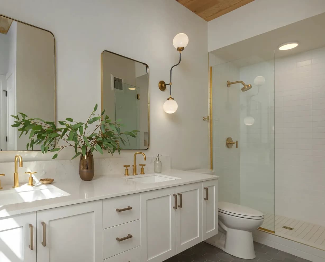 Finished bathroom lit by a brass globe sconce at the vanity and recessed fixtures over the shower