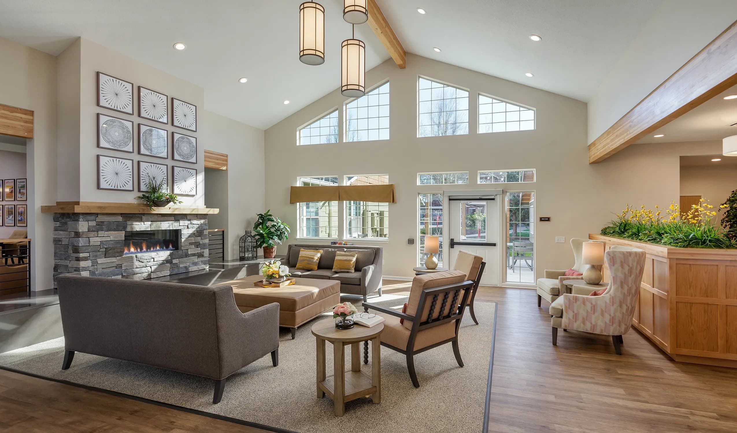 A vaulted common lounge with pendant lighting, recessed downlights and a lit fireplace