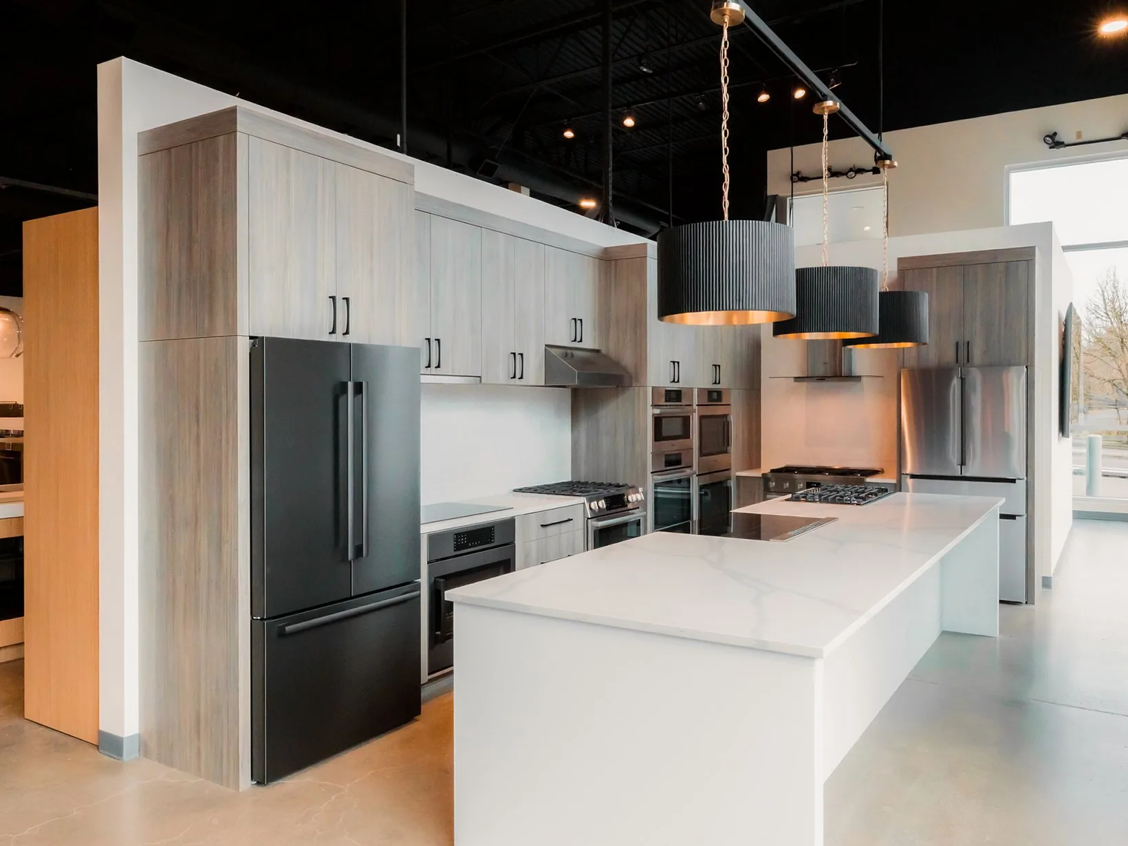A finished commercial kitchen fit-out, pendant lights over the island and appliances installed